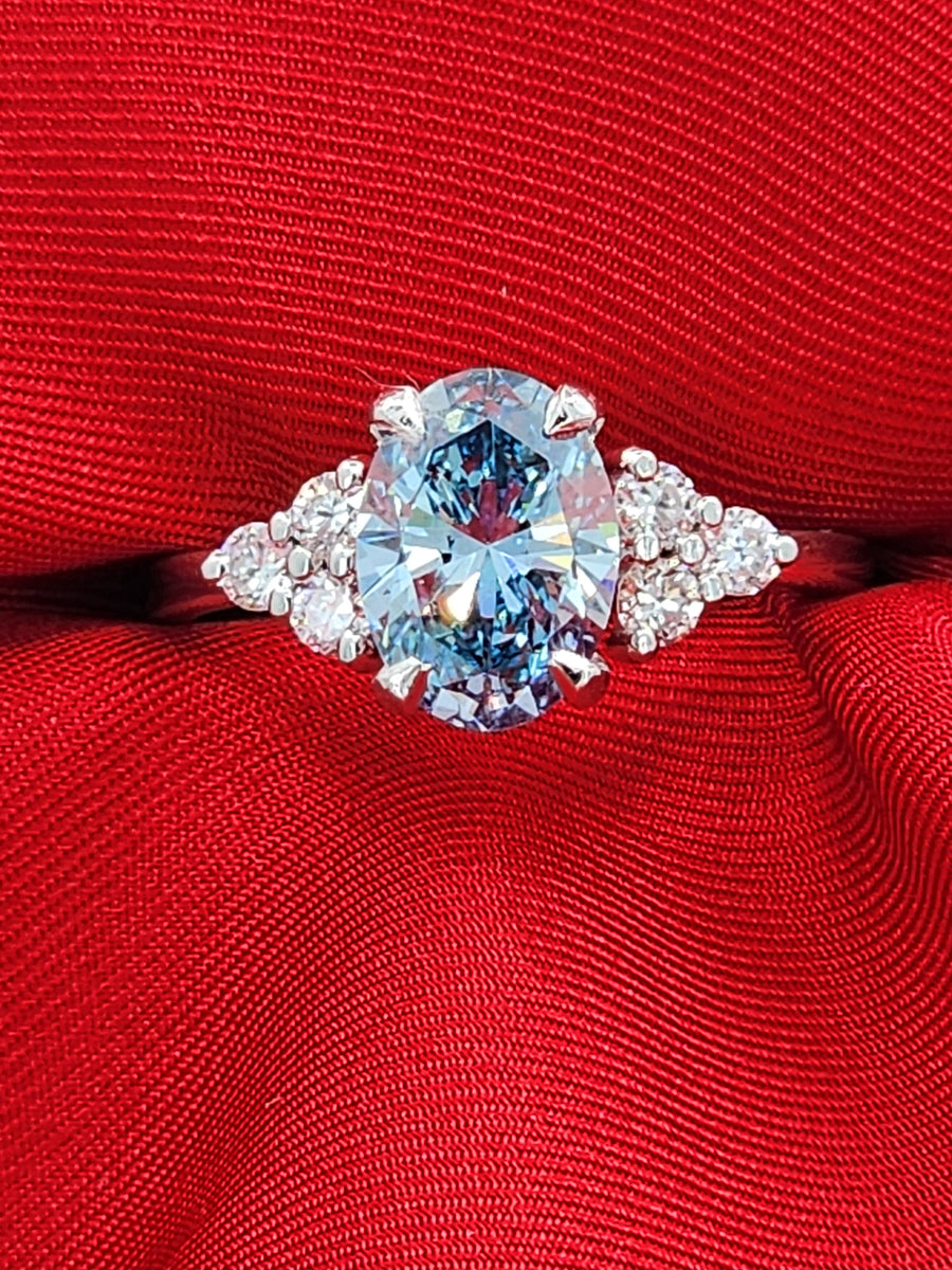 Blue lab grown oval cut diamond ring with a 2-carat center stone, showcasing its brilliance and sleek modern setting in a straight front view.