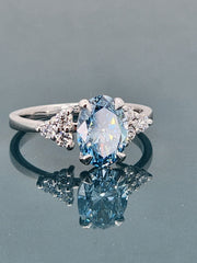 Angled perspective of a blue lab-grown oval cut diamond ring, emphasizing the depth and brilliance of the 1.95-carat center stone.

