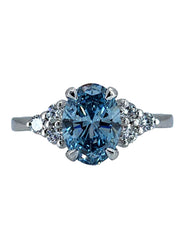 Detailed close-up of a blue lab-grown oval cut diamond ring, capturing the facets and sparkle of the 1.95-carat center stone.

