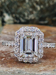 2.31 carat lab grown emerald cut diamond ring captured in outdoor lighting, highlighting the clarity of the center stone and shimmering halo setting.

