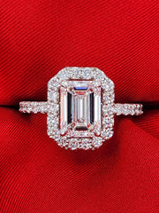 Lab grown emerald cut diamond ring with halo design displayed against a bold red fabric, showcasing brilliance and sparkle in a 2.31 carat center stone.